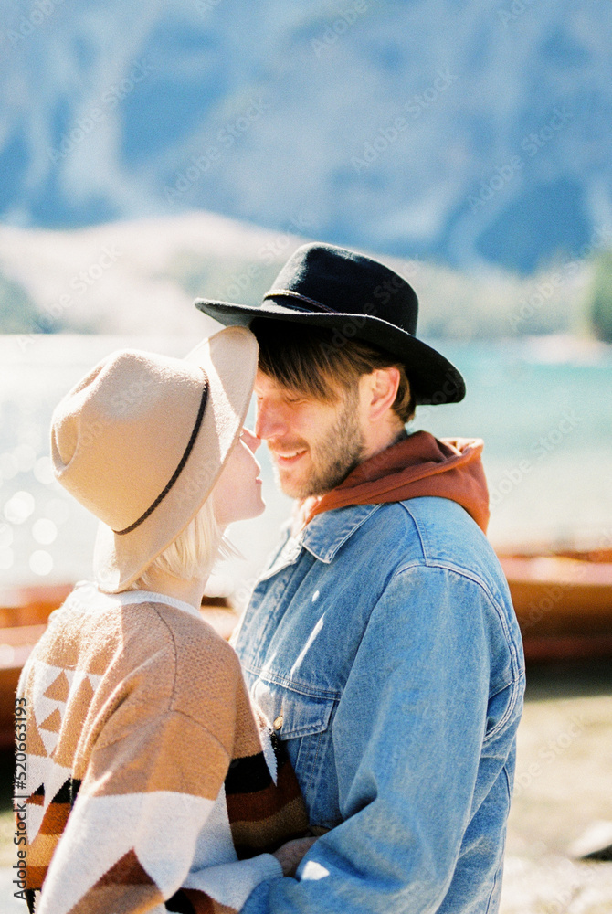 Man hugs a woman in a hat near Lake Braies. Italy