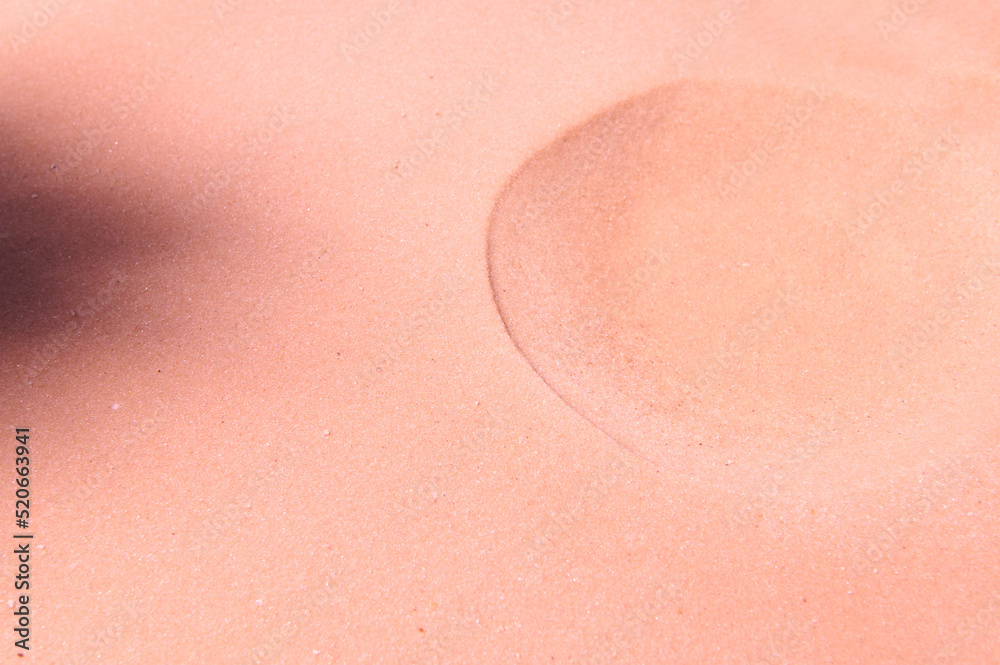 A formed crater on pure pink sand. Sandy background. Copy space for promotional and advertising text A formed crater on pure pink sand. Sandy background. Copy space for promotional and advertising text