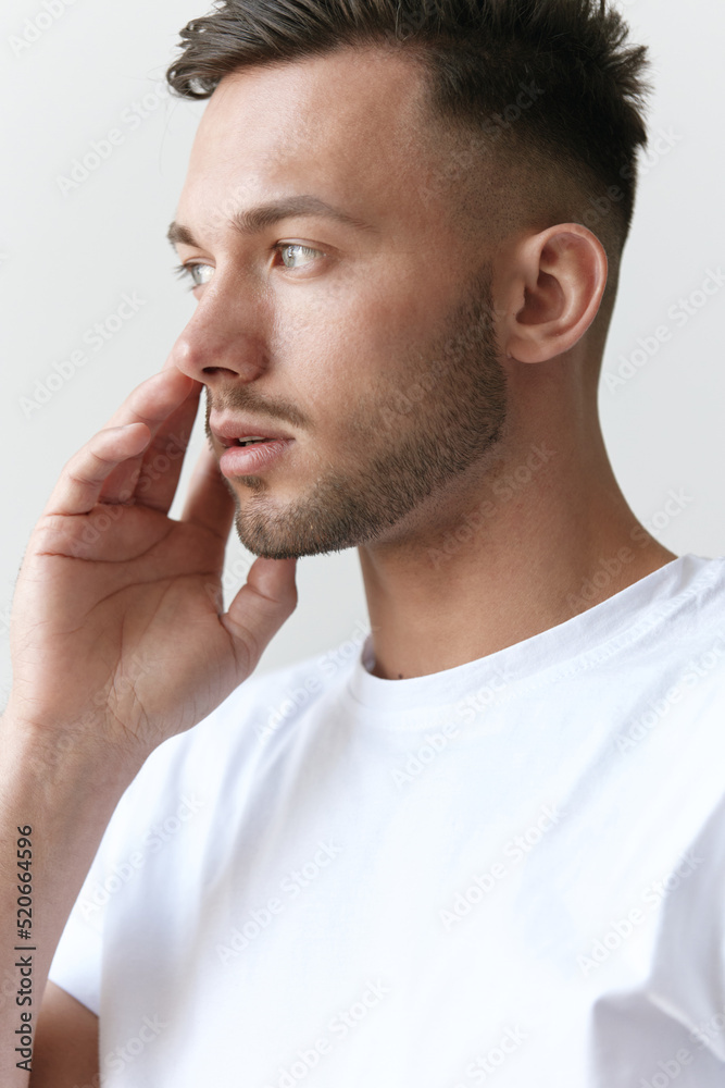 Portrait shot of handsome pensive romantic serious tanned man guy in basic t-shirt looks aside posing on white background. Fashion Style New Collection Offer. Copy space for ad. Model snap Portrait shot of handsome pensive romantic serious tanned man guy in basic t-shirt looks aside posing on white background. Fashion Style New Collection Offer. Copy space for ad. Model snap