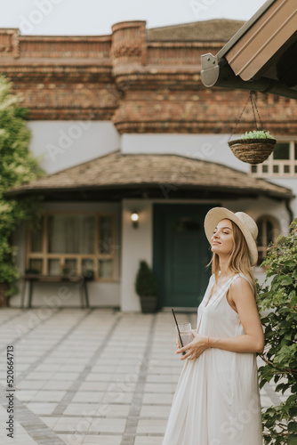 Young woman with hat drinki...