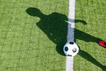 Soccer football sport background. Soccer ball and shadow of player on artificial turf soccer field in sunny day outdoors