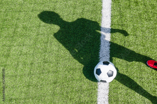 Soccer football sport background. Soccer ball and shadow of player on artificial turf soccer field in sunny day outdoors © vejaa