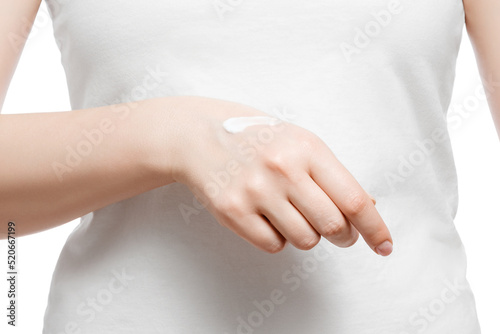 Close up shot of a woman in white t-shirt applying hand cream, isolated on white. Well-groomed short natural nails.