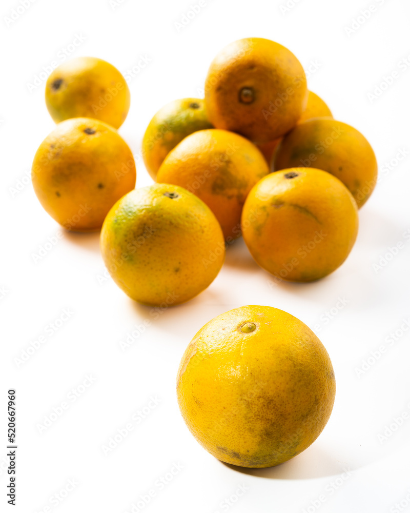 lot of yellow oranges on a white background one in the foreground the rest in the background