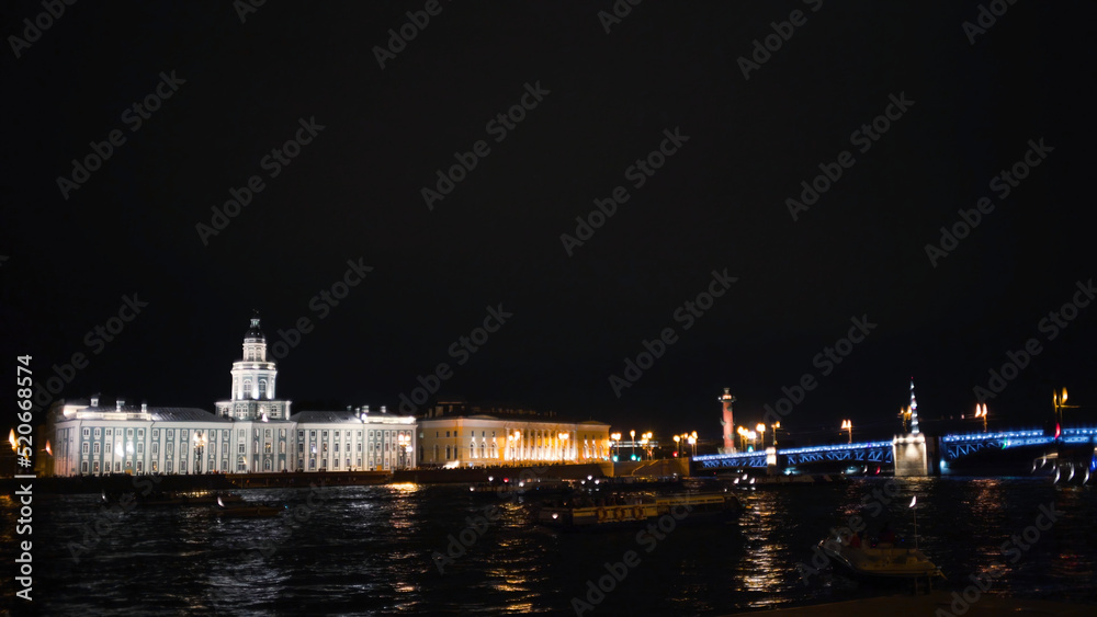 Busy river on background of ancient architecture and bridge at night. Action. Lot of boats floating on night city river with old luminous architecture. Night city river