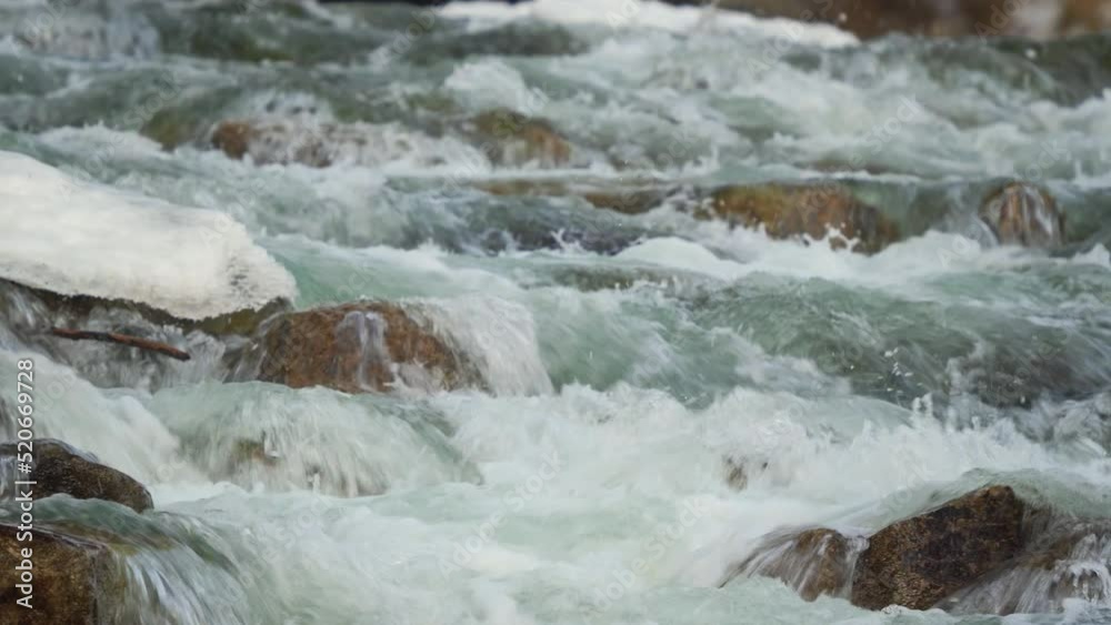 Winter river flowing near snow and ice covered stones, closeup detail Winter river flowing near snow and ice covered stones, closeup detail
