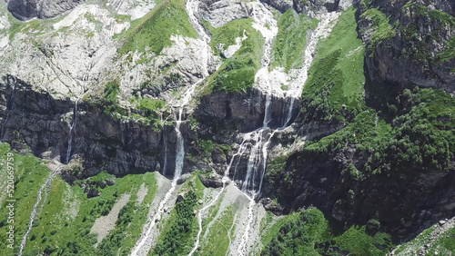 Waterfall flowing down from high mountains on a Sunny day. Top view of the mountain from which the river flows photo
