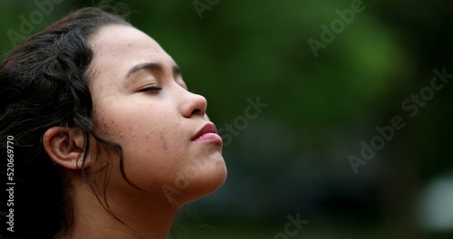 Young woman face opening eyes in meditation and contemplation loooking up at the sky with hope and faith