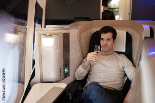 Male businessman holding glass of champagne on first class busines flight