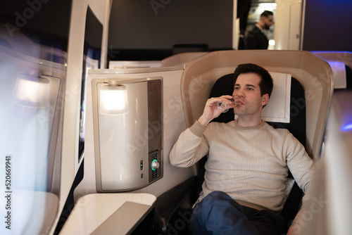 Young rich man on board of first class drinking champagne, enjoying financial success. photo