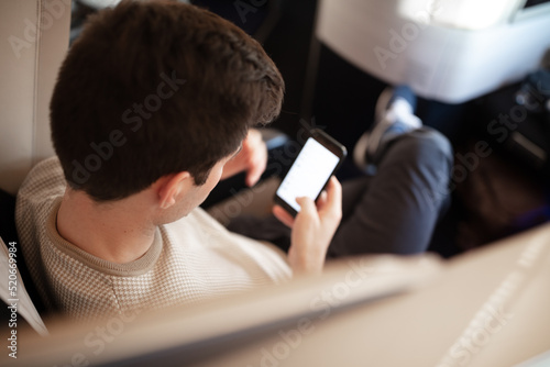 Man flying business class and working on phone during flight