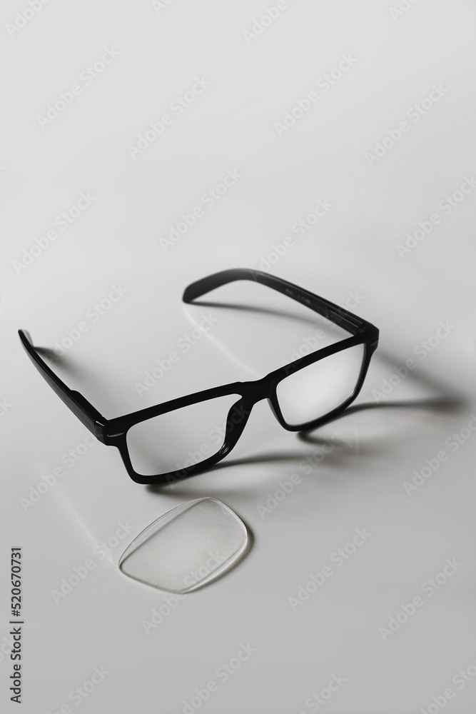 Broken pair of black reading glasses set against a white background with copy space available Broken pair of black reading glasses set against a white background with copy space available