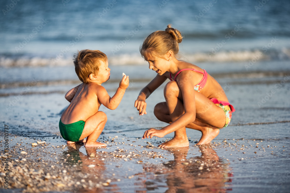Older sister playing with younger brother aground near the shore on summer vacation Older sister playing with younger brother aground near the shore on summer vacation