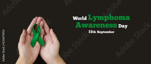Adult hands holds green ribbon on black background. World lymphoma awareness day. September 15. Liver, Gallbladders bile duct, kidney Cancer and Lymphoma Awareness month.