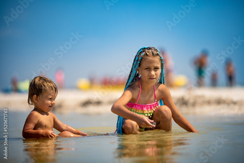 Older sister playing with younger brother aground near the shore on summer vacation © YouraPechkin