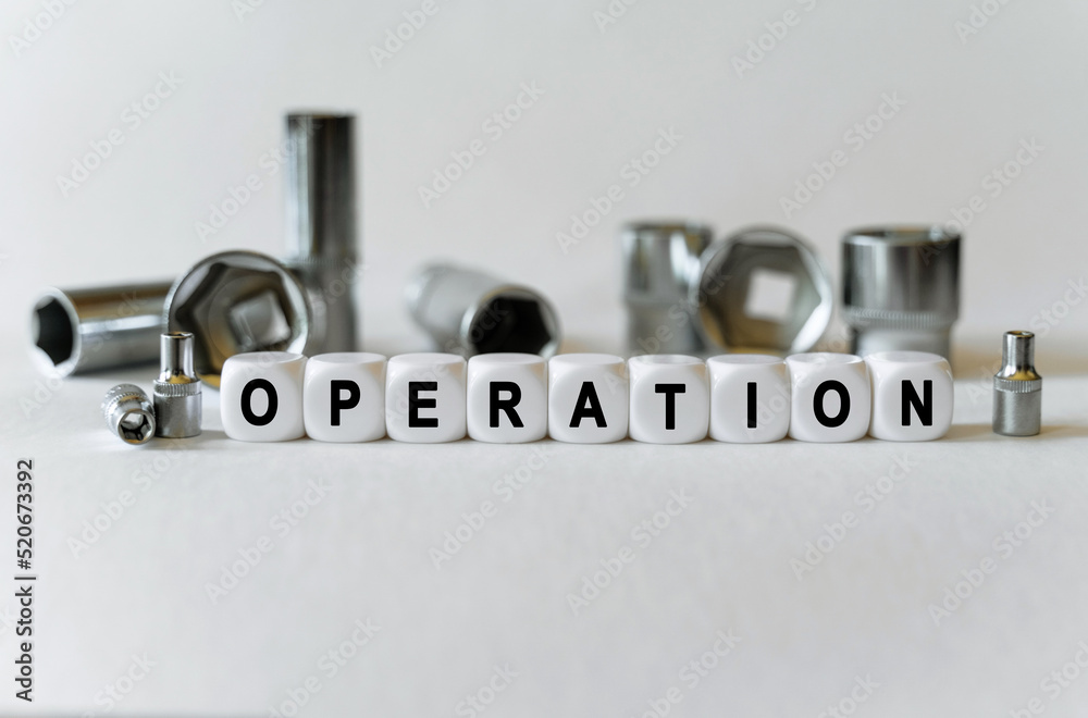 On a white background, a set with tools and white cubes with the inscription - operation On a white background, a set with tools and white cubes with the inscription - operation