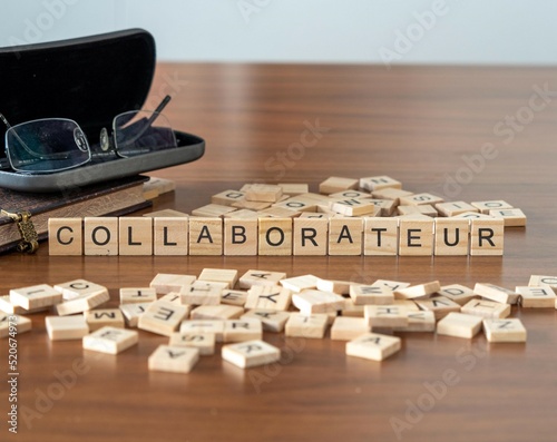 collaborateur mot ou concept représenté par des carreaux de lettres en bois sur une table en bois avec des lunettes et un livre