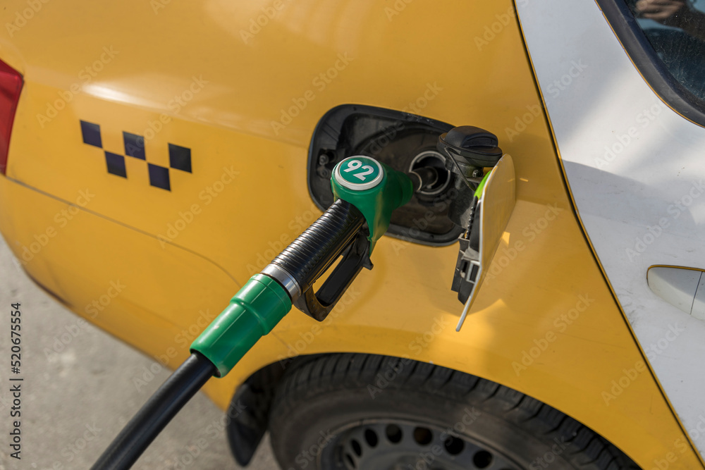 An auto-refueling nozzle is inserted into the tank of a taxi car.