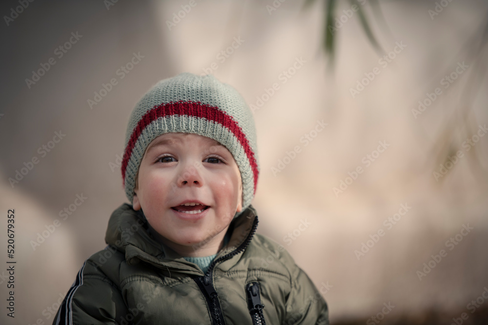 Niño bebé con gorro de lana sonriendo y mirando a la cámara Niño bebé con gorro de lana sonriendo y mirando a la cámara