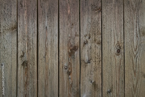 Old grey weathered outside wall of rustic barn covered with vertical worn wooden planks for texture or background.