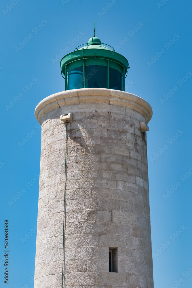 Small stone-made lighthouse at the harbourfront of Cassis, France in front of a clear blue sky on a summer day. Vacation destination on the Côte d Azur.