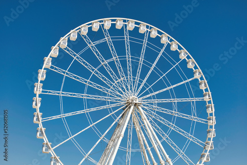 Big  tall white Ferris wheel in front of a perfect blue sky at the oceanfront in Marseille  France. Happy summer vacation feelings. 