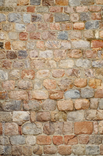old brick wall. a wall, which is an old, antique masonry of stones of different sizes and colors. Castle wall, old building. vertical photo