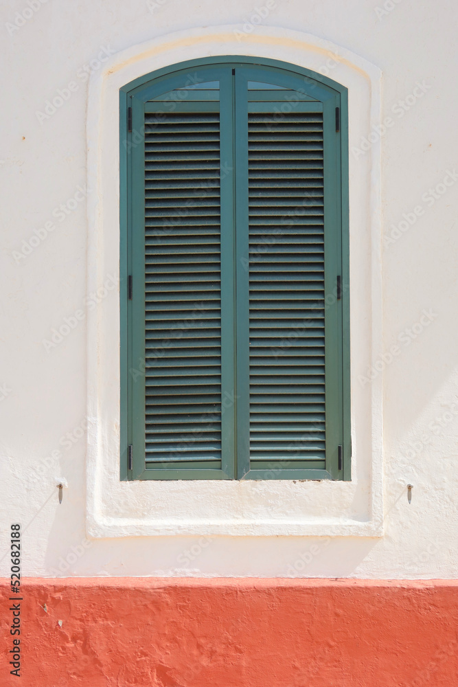 A window in an old building with green shutters. Green closed shutters. Minorca, Spain