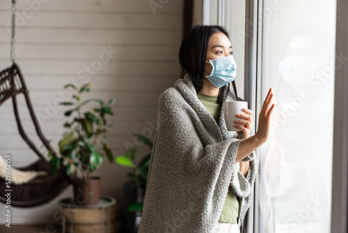 Fotografia Asian girl in medical face mask, yearning go outside, being sick with covid 19 a