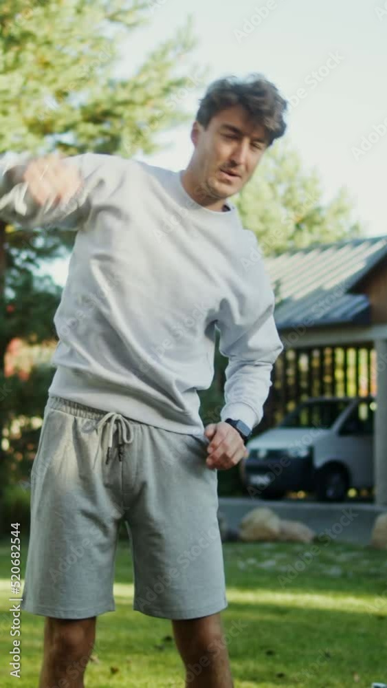 A young man in sportswear exercises in the fresh air near a modern mansion A young man in sportswear exercises in the fresh air near a modern mansion