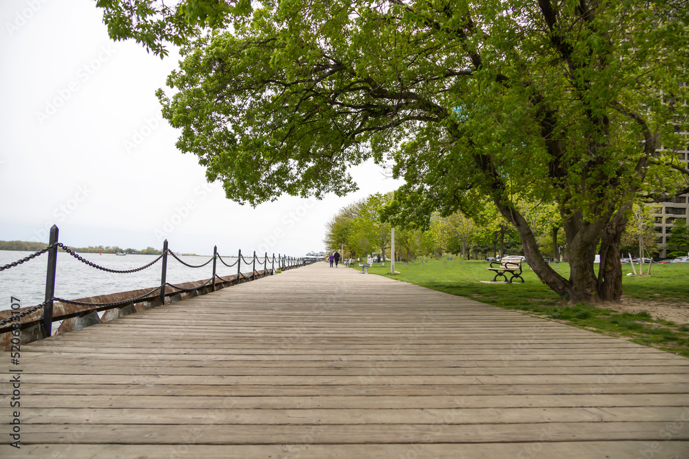 Fototapeta premium Pedestrians walking on a wooden boardwalk by the ocean