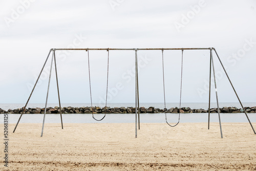 Metal swings on a sandy beach near the ocean