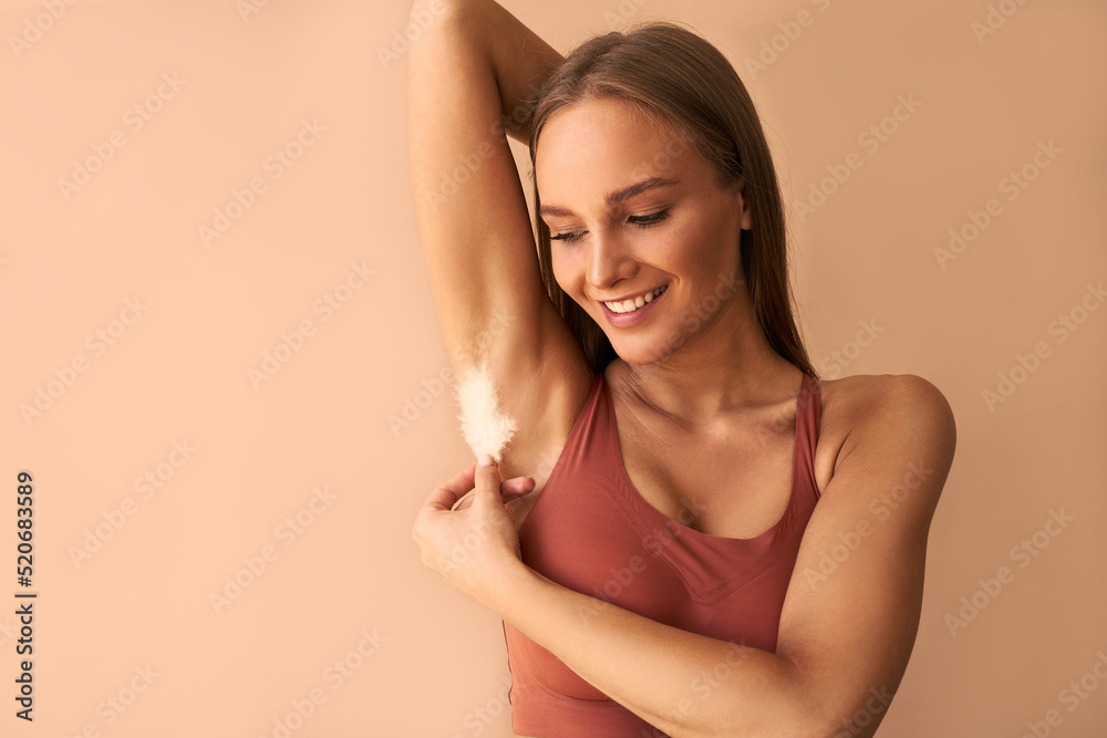 Portrait of a beautiful young woman posing with feathers under her on beige background.Smooth skin, depilation. Portrait of a beautiful young woman posing with feathers under her on beige background.Smooth skin, depilation.