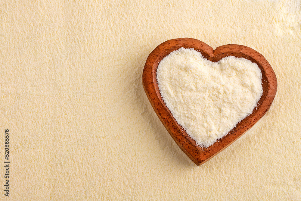 Powdered or dehydrated milk in the heart-shaped bowl Powdered or dehydrated milk in the heart-shaped bowl