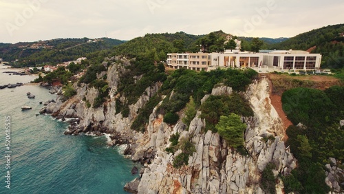 Kassandra Cliffs and a white building seen from bird's eye perspective from the direction of the sea. Cloudy sky. High quality photo