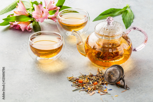 Photography Hot lemongrass tea in a glass teapot on a light background decorated with flower