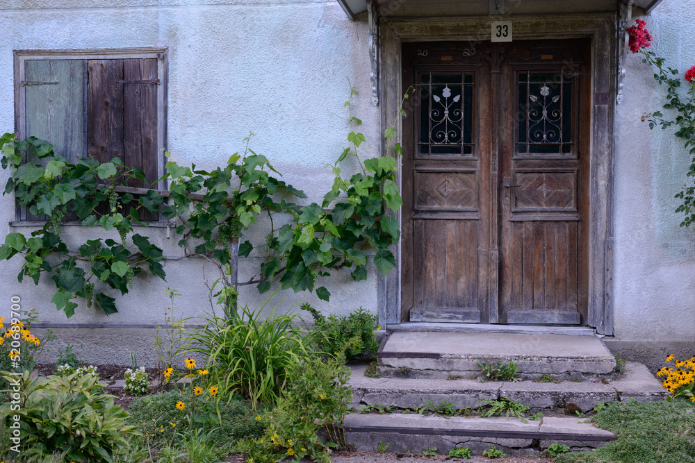 Ornate entrance door of an old farmhouse with traditional front garden, southern Germany Ornate entrance door of an old farmhouse with traditional front garden, southern Germany