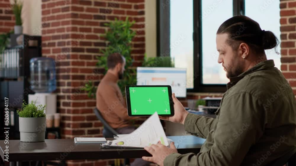 Male freelancer using horizontal greenscreen display on tablet, looking at blank chroma key template with isolated mockup background and copyspace. Digital gadget with technology. Male freelancer using horizontal greenscreen display on tablet, looking at blank chroma key template with isolated mockup background and copyspace. Digital gadget with technology.