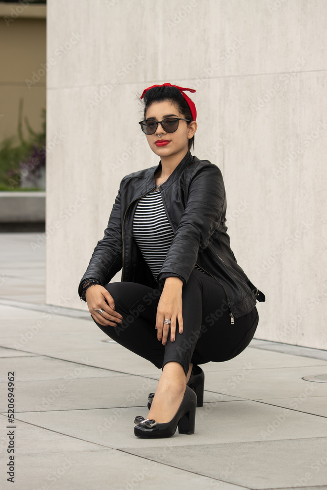 Rockabilly girl on vespa and modeling pinup style at urban city. Pin up and  black clothes girl. Stock Photo