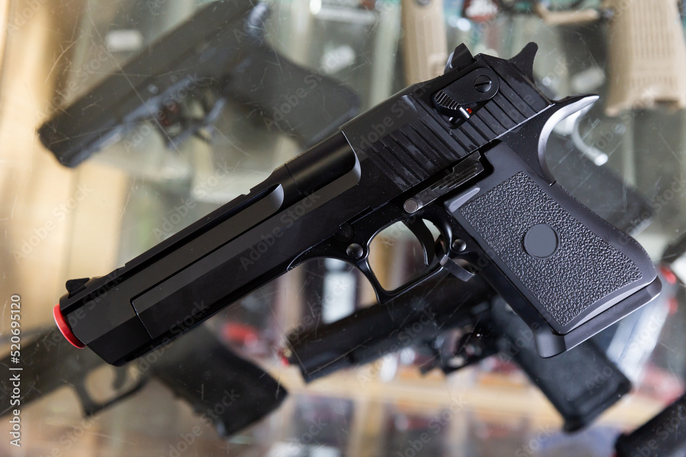 Replica of handgun on showcase in military goods store. Airsoft weapon ...