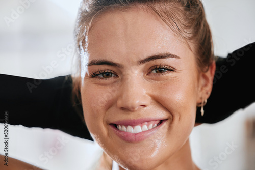 Face of healthy, fit and active woman smiling and looking relaxed, carefree and happy inside. Head closeup of .beautiful, attractive female athlete taking break after hard and sweaty fitness workout photo