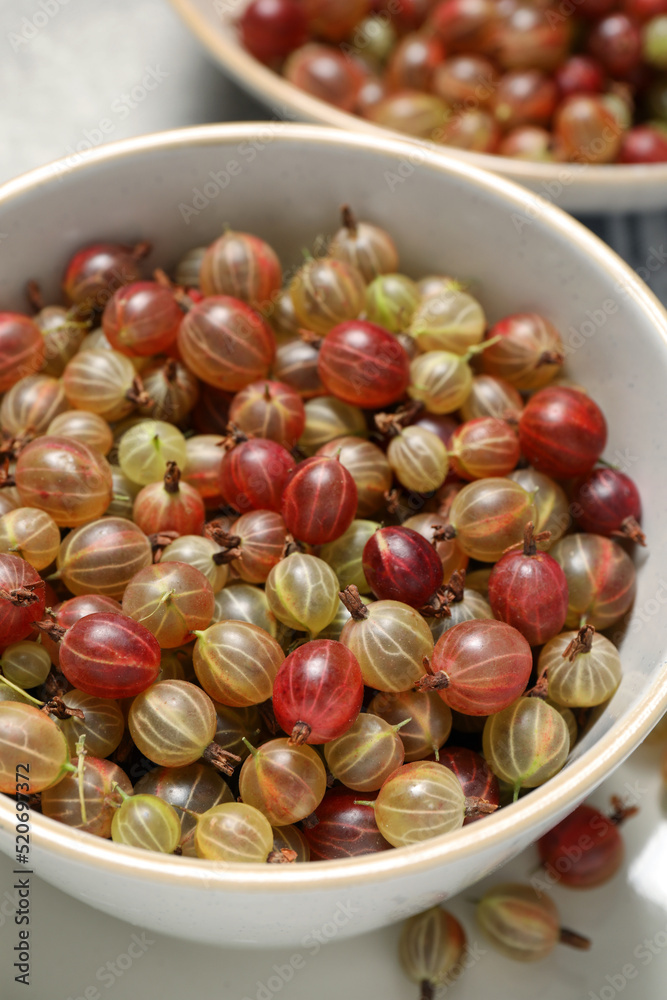 Fresh ripe gooseberries in bowls on light table, closeup Fresh ripe gooseberries in bowls on light table, closeup