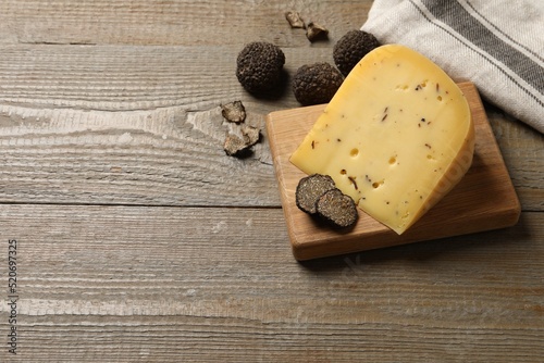 Delicious cheese and fresh black truffles on wooden table, above view. Space for text