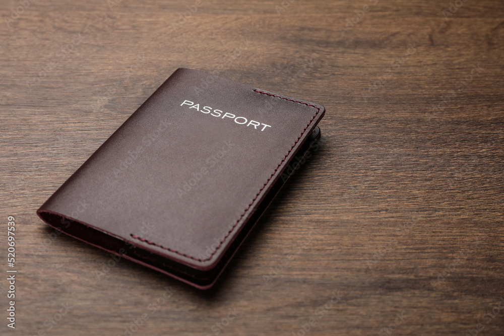 Passport in brown leather case on wooden table. Space for text Passport in brown leather case on wooden table. Space for text