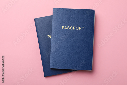 Blank blue passports on pink background, flat lay photo