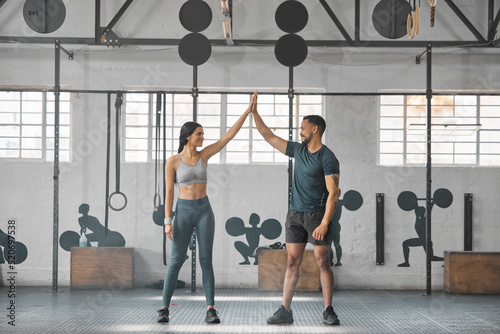 Fit, active and healthy sports athletes training together in gym workout room, living a strong wellness lifestyle. Male and female fitness instructors high five and smiles in physical exercise class
