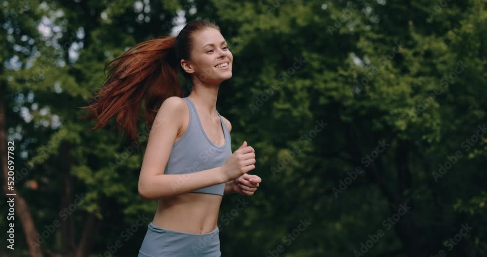 Woman on a morning jog in the park in a tracksuit against a background of trees