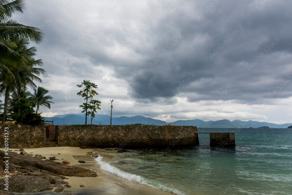 Palm trees in a beach and dark clouds at the coast of Angra dos Reis town, State of Rio de Janeiro, Brazil. Photo taken with Nikon D7100, 18-200 lens, at 18mm, 1/50 f 22.0 ISO 100. Date Jan 3, 2017