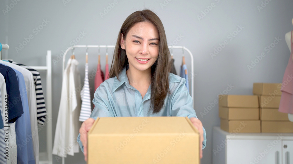 Beautiful Asian woman packing a postal package on the table, online shopping and e-commerce in small start up business concept. Beautiful Asian woman packing a postal package on the table, online shopping and e-commerce in small start up business concept.
