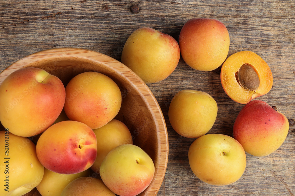 Fresh ripe juicy yellow orange red apricot fruit pile whole cut half slice seed in wooden bowl on rustic wood background flat lay top view Fresh ripe juicy yellow orange red apricot fruit pile whole cut half slice seed in wooden bowl on rustic wood background flat lay top view